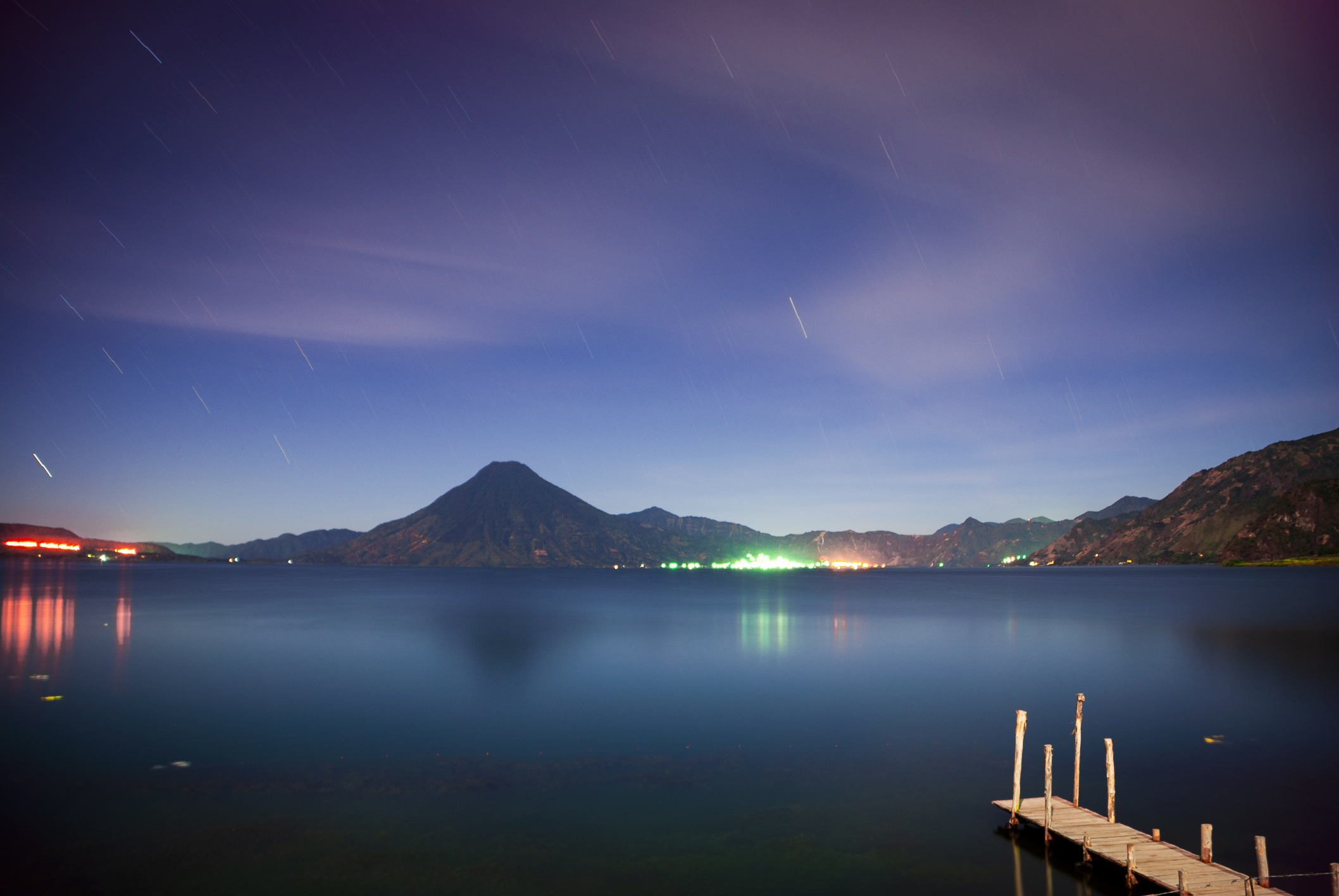 A cool mountain lake at night beneath stars and volcanic silhouettes.